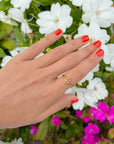 Open Cross Gold-Tone Ring worn on a hand with coral nails beside white flowers