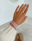 Dusty rose WWJD embroidered bracelet worn on a wrist with a cream knit sleeve