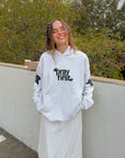 Front view of Pray First Heather Grey Hoodie styled with a white skirt outdoors