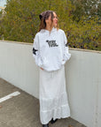 Woman wearing relaxed Pray First Heather Grey Hoodie with a long white skirt