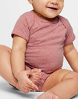 Baby wearing a pink onesie sitting on a white background