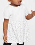 Child wearing a white dress with a polka dot skirt on a plain background