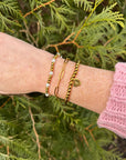 Renewal bracelet set styled on a wrist with a pink knit sleeve against greenery