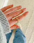 Hand wearing the gold-tone Ribbon Bow Ring beside a gray sweater sleeve.