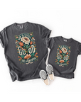 Two dark gray t-shirts with floral design and text, paired with checkered shoes on a white background.