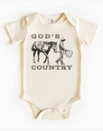 A white bodysuit onesie with 'GOD'S COUNTRY' printed in black. The design includes an illustration of a horse and a cowboy riding a horse.