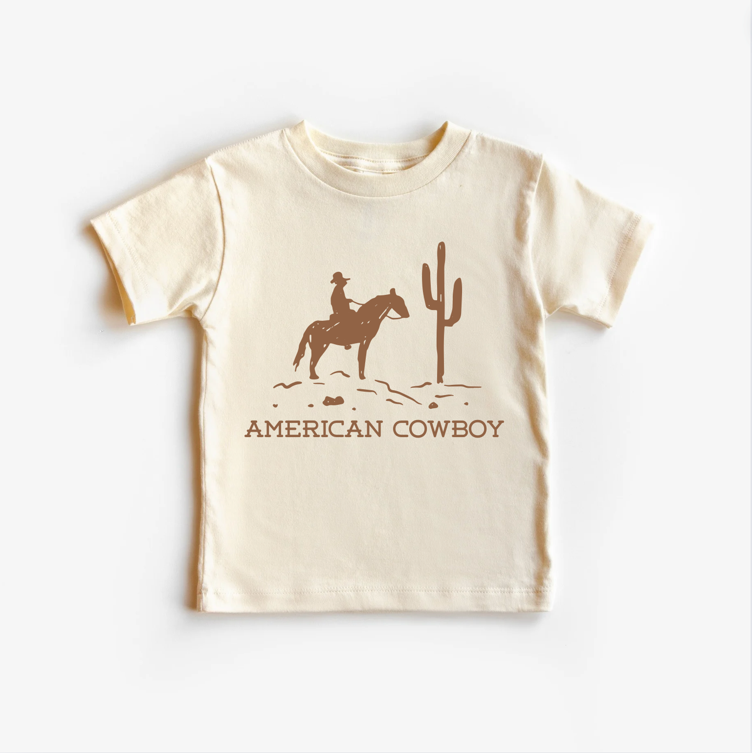 A beige neutral tee shirt top with an illustration of a cowboy on a horse and cactus design.