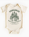 A white bodysuit with green trees and text that reads 'Congaree National Park, Established November 19, 2004, South Carolina'.