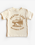 A beige unisex tee shirt with 'CRATER LAKE NATIONAL PARK OREGON' printed on the front.
