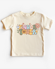 A white unisex gender-neutral tee shirt top with 'Flower Power' text and colorful floral illustrations on it, suitable for children.