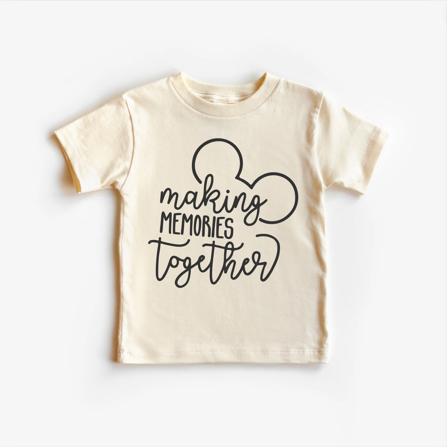 A beige neutral tee shirt top with text 'MAKING MEMORIES TOGETHER' and a silhouette of a mouse character on the front.