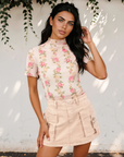 Model wearing the Millie floral mock neck mesh top tucked into pale pink shorts.