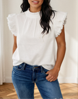 Close-up of the white Logan top showing the ruffled collar and flutter sleeves