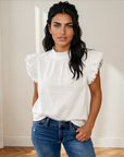 Model wearing the white Logan flutter sleeve top with a ruffled collar and blue jeans