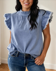 Logan blue denim top with ruffled flutter sleeves and a delicate ruffled collar, styled with jeans