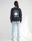 Back view of the Spirit Is Moving black tee with a large white dove graphic, styled with light-wash jeans