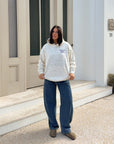 Full-length view of a model wearing the ivory wildflower hoodie with jeans outdoors