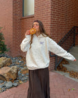 Model wearing the ivory Talk to God wildflower hoodie outside a brick building