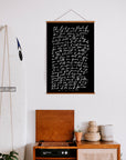 Black Psalm 23 scripture poster with white lettering and wooden hanging rails above a wooden cabinet.