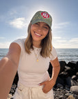 Smiling model wearing the WWJD camouflage cap beside the ocean