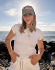 Model styling the WWJD camo baseball cap with a light-colored outfit on a rocky shoreline