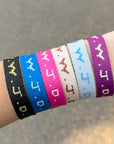 Wrist wearing multiple colorful wristbands with text on a blurred background