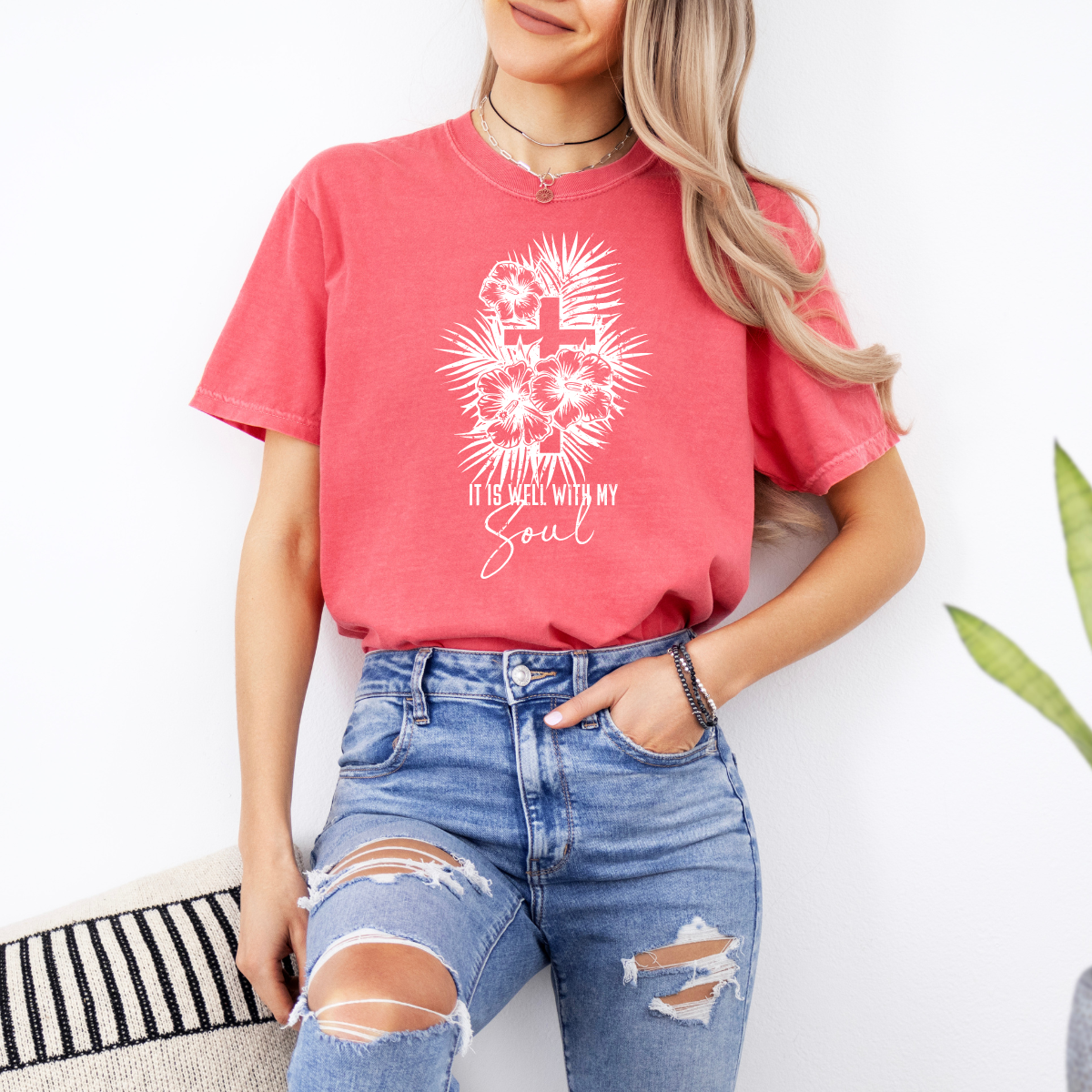 Person wearing a red t-shirt with a white graphic design and text, standing against a white background.