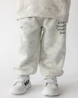 Front view of white camo kids’ sweatpants with What a Friend We Have in Jesus lettering, worn with white sneakers