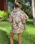 Outdoor back view of the What a Friend in Jesus Camo Shacket showing embroidered lettering.