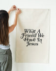 Person holding a banner with text 'What A Friend We Have In Jesus' against a white wall
