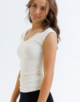 Woman wearing a white sleeveless top and black pants on a white background