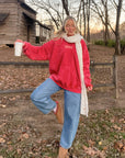 Yahweh Ribbon Red Hoodie styled with blue jeans and a long cream scarf outdoors