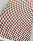 Checkered brown and white crib sheet on a white crib