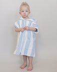 Child wearing a blue and white striped towel on a plain background