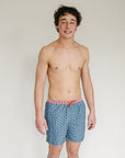 Man wearing blue patterned swim shorts with a white background
