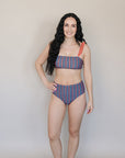 Woman wearing a patterned bikini standing against a plain background