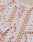 Folded fabric with orange leaf pattern on a beige background