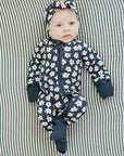 Baby in a floral onesie and headband lying on a striped fabric background