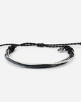 Black braided bracelet with a silver charm on a white background