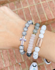 Three bracelets on a wrist with a brick background