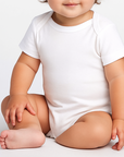 Baby girl modeling the Bella Canvas 100B infant jersey one piece in a neutral studio setting, front view