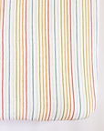 Fitted crib sheet with multicolored stripes on a white background