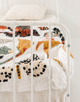 White metal bed with colorful bedding against a plain white wall