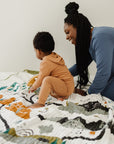 Woman and child playing on a colorful quilt against a white wall