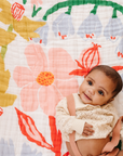 Baby sitting on a colorful floral-patterned blanket