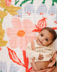 Baby sitting on a colorful floral-patterned blanket