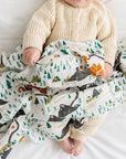 Baby lying on a white blanket with a patterned blanket draped over them