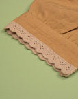Close-up of the mustard puff sleeve with decorative scalloped trim.