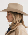 Woman wearing a beige hat and coat on a white background