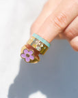Hand holding a small decorative item with a flower design on a white background